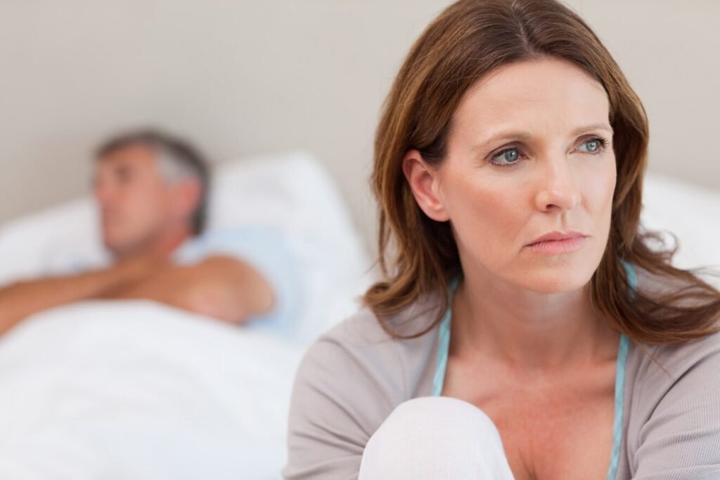 Assenza di orgasmo femminile: 5 verità da conoscere per ritrovare il piacere 2 Donna seduta ai piedi del letto con sguardo triste – rappresentazione simbolica della difficoltà nel provare piacere femminile e del disagio emotivo legato alla sessualità